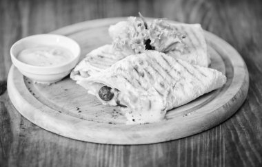 Lavaş burrito doldurulmuş et sosisi ve peynir sosu salata servisi yapıyordu. Lavaş burrito ile sarılmış et. Restoran yemeği. Geleneksel mutfak. Burrito tortilla tahtadan yapılmış. Restoran yemekleri konsepti.