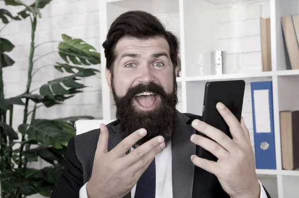 Tengo buenas noticias. Feliz teléfono móvil profesional. Hombre barbudo con mirada feliz en la oficina. Empresario exitoso. Feliz negocio. Buen trato. — Foto de Stock