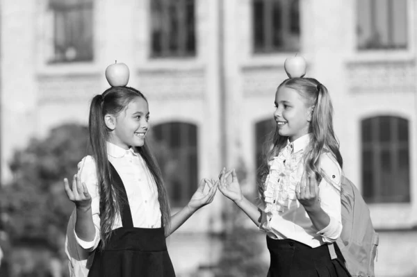 Smiling girls school clothes with apples on top of heads, peaceful kids concept — Stock Photo, Image