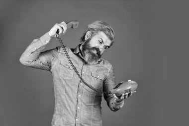 Reklamcılığın geleceği. Son sınıf hipster 'ı eski telefonu gösteriyor. Telefonu olan acımasız bir adam. Olgun sakallı adam retro telefonda konuşuyor. Modern yaşamda klasik teknoloji. Genç adam telefonda konuşuyor.