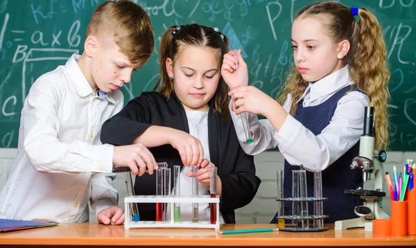 Μικρά παιδιά μαθαίνουν χημεία στο σχολικό εργαστήριο. φοιτητές που κάνουν πειράματα βιολογίας με μικροσκόπιο. Ημέρα των παιδιών. Χημεία. Πίσω στο σχολείο. Μικρά παιδιά στο σχολείο. Φαρμακοποιός με αυτοπεποίθηση — Φωτογραφία Αρχείου