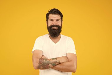 Sarı arka planda mutlu vahşi sakallı adam. Yakışıklı, kendine güvenen bir adamın mükemmel bir saç stili var. Erkek yüz bakımı. Vahşi sakallı adamın portresi. Düşünen şık adam gülümsüyor.