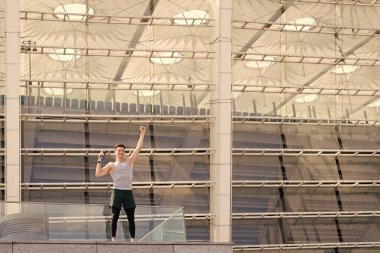 Yeni şampiyon. Spor kıyafetli yakışıklı genç adam elinde bir şişe su tutuyor. Mutlu sporcu başarılı oldu. Sağlıklı yaşam ve kendini kontrol kavramı. Su iç. Formda ve sağlıklı kalmak.