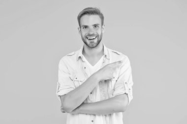 pozitif mutlu adam işaret ediyor ve sarı arka planda kot giyip ürün sunuyor.