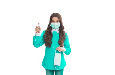 Doktor kız alkol bazlı el yıkama spreyi kullanıyor. Solunum maskeli bir çocuk. Koronavirüse karşı koruyucu önlem. Antibakteriyel dezenfektan jeli. Dezenfektan jeliyle el temizleme