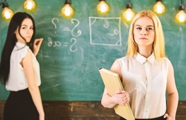 Öğrenciler ve stajyerler konsepti. Kadın tahtaya yazı yazarken kendinden emin görünüyor. Odaklanamıyor. Öğrenci, resmi giyinen öğretmen sınıfta dursun. Derse hazırlanan çekici kadınlar.