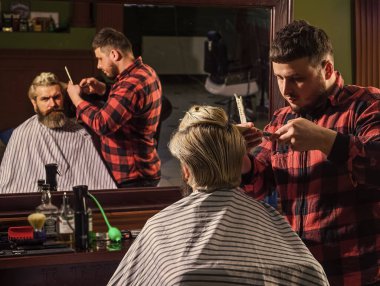 Uzun sarı saçlı adam, dikiz aynasından bakıyor. Kendini uyarılmış say. Hipster müşteri saçını kestiriyor. Berber makası. Saç kes. Berber, sakallı adam için kuaförlük yapıyor.