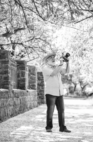 Viagem de aposentadoria. Férias. Desfrutando de tempo livre. Andar na sua rua favorita. Viagens e turismo. Foto de viagem. Fotógrafo no jardim florescente. Capturar a beleza. Senior homem segure câmera — Fotografia de Stock