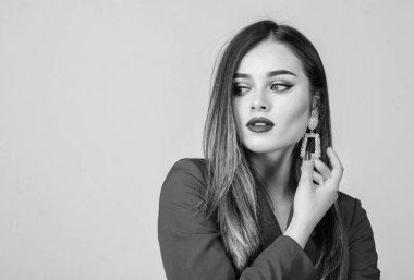 Mücevher dükkanı. Altın takı küpelerini gösteren uzun saçlı bir model kız. Pahalı bir aksesuar. Modaya uygun mücevherler. Kusursuz makyaj ve mükemmel mücevherler. Kadın göz kamaştırıcı küpeler takıyor. Moda eğilimi