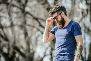 UV filtresi. Sakallı hippi vahşi adam koruyucu güneş gözlüğü takıyor. Güneş gözlüklü, sakallı, doğa geçmişi olan bir adam. Hippi koyu güneş gözlüklerine güveniyor. Sakallı adam modern güneş gözlüğü takıyor.