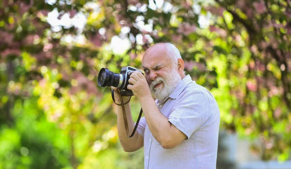 Creating memories for lifetime. Emotions through photos. Hobby and leisure. Experienced photographer in spring garden. Senior man shoot in nature. Cameraman outdoors. Photographer shooting nature — Stock Photo, Image