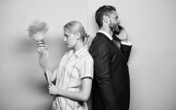 La routine ménagère. Femme au foyer et homme d'affaires. Carrière et ménage. Couple familial. Femme stand avec brosse à poussière mari a conversation téléphonique. Deux hommes et une femme. Entretien ménager ou entreprise — Photo