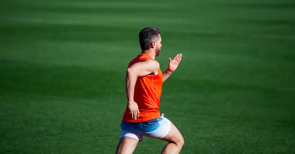 Energieke atletische gespierde man loper lopen buiten op groen gras, joggen — Stockfoto