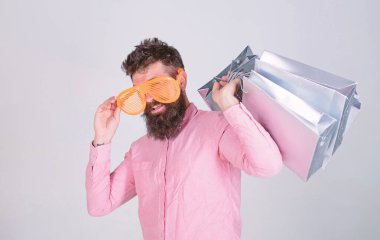 Alışverişe bağımlı tüketici. Bir sonraki tatiline nasıl hazırlanacağını. Sakallı hippi adam güneş gözlüğü takıyor, alışveriş torbası tutuyor. Kara Cuma 'da alışveriş. Kese kağıdıyla iyi alışverişler