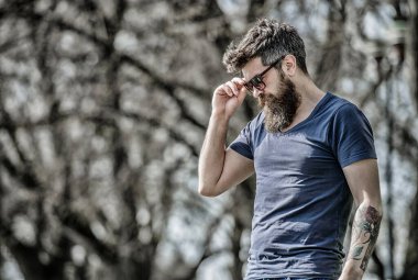 UV filtresi. Sakallı hippi vahşi adam koruyucu güneş gözlüğü takıyor. Güneş gözlüklü, sakallı, doğa geçmişi olan bir adam. Hippi koyu güneş gözlüklerine güveniyor. Sakallı adam modern güneş gözlüğü takıyor.