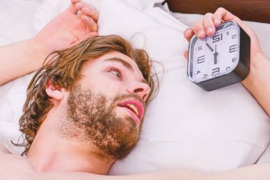 Adam yatakta uzanıyor. Genç bir adam yatakta uyanıyor ve kollarını açıyor. İnsanlar, uyku zamanı ve dinlenme konsepti - evde yatakta adam.