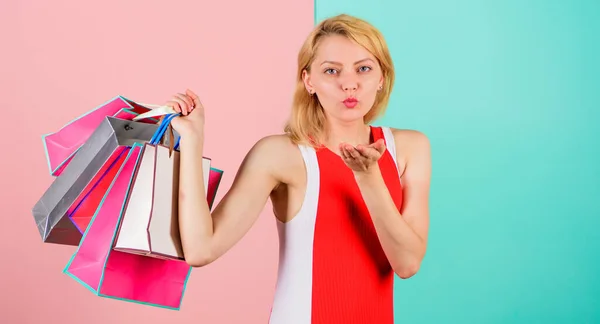 Tipps für einen erfolgreichen Einkauf. Mädchen kaufen gerne ein oder haben gerade Geburtstagsgeschenke bekommen. Frau rotes Kleid halten Bündel Einkaufstüten blau rosa Hintergrund. Kaufen Sie alles, was Sie wollen. Mädchen zufrieden mit dem Einkaufen — Stockfoto