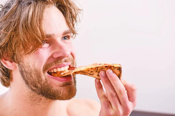 Jovem descansando em casa com um nu e uma pizza. Jovem bonito sem camisa com pizza na cama. Quem se importa com a dieta? Cama de pizza. — Fotografia de Stock