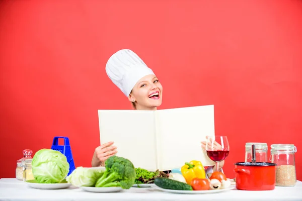Meisje koken aan keukentafel ingrediënten. Tips en advies. Eten klaarmaken. Heerlijk en gastronomisch. Eten koken als hobby. Koken op zoek naar koken recept in kookboek. Vrouw leest kookboek in de keuken — Stockfoto