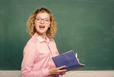 Bilgiye karşı tutkulu. Pedagog kitabı tutuyor ve bilgiyi açıklıyor. Eğitim konsepti. Öğretmen zor konuyu açıkla. Öğrencilerin en iyi öğretmeni. Karatahtanın önündeki kadın öğretmen.