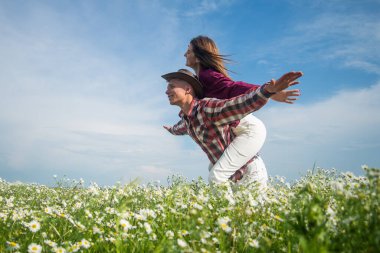 Bahar doğası güzeli. Aşk ve romantizm. Romantik ilişki. Birbirine aşık güzel bir çift. Papatya çiçeği tarlasında kadın ve erkek. Yaz tatili. Çiçekler arasında mutlu bir aile. Neşeli çift.