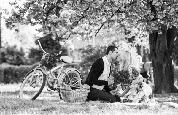 Carefree time together. summer holiday trip. girl and man under sakura. couple in love drinking wine at dinner in park. picnic of couple in love at vintage bike. family relationship and friendship