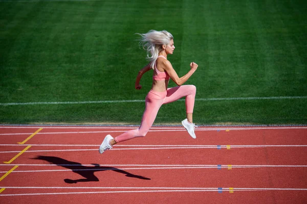Wysportowana kobieta w stroju fitness biegająca na stadionie, wytrzymałość — Zdjęcie stockowe