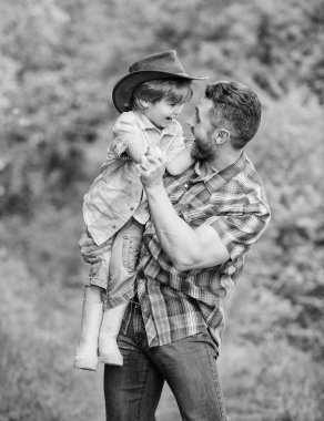 Küçük çocuk çiftçilikte babasına yardım ediyor. Baba oğul çiftlikte kovboy şapkası takıyor. Lastik çizmeli çocuk. Ormanda mutlu bir baba. İnsan ve doğa. Aile günü. Dünya günün kutlu olsun. Eko çiftliği. Aile zamanı