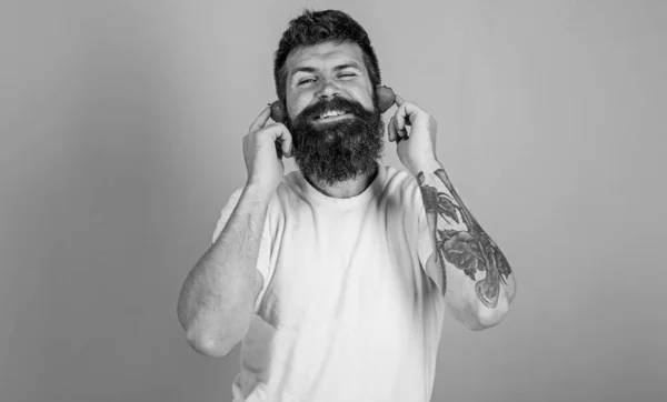 Homme barbu hipster oreilles de fraise mûres rouges comme écouteurs. Top des radios estivales. Guy profiter du son juteux de la musique de la chanson d'été. Barbe hipster écouter de la musique écouteurs fraise. Concept de hit d'été — Photo