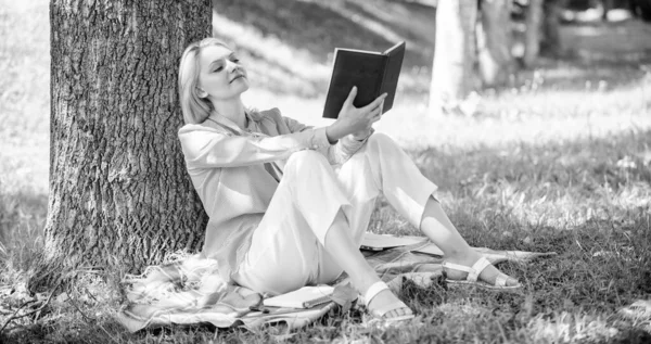 Self improvement and education concept. Business lady find minute to read book improve her knowledge. Female self improvement. Girl lean on tree while relax in park sit grass. Self improvement book