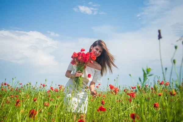 夏の花の草原。ケシの中で美しい女性。アヘンだ。幸せな女の子が春の花束を集める. — ストック写真