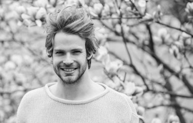 Bahar sezonu. Botanik ve doğa. Mutlu bahar konsepti. Hippi çiçek aromasının tadını çıkarır. Tıraşsız bir adam manolya çiçeği koklar. İlkbahar konsepti. Erkek çiçekli arka plan çözüldü. Bahar güzeli