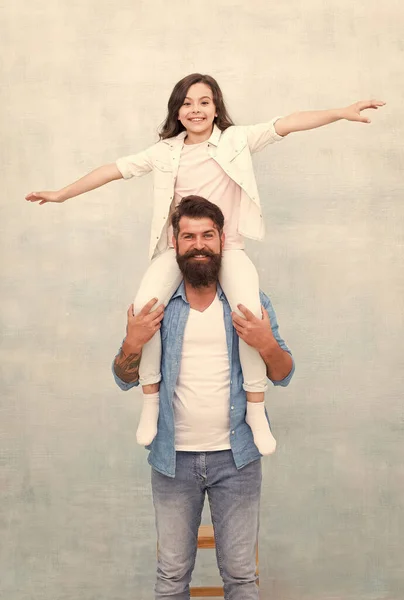 Feliz padre paseo hija niño en hombros pretendiendo vuelo jugando avión gris fondo, padres día — Foto de Stock