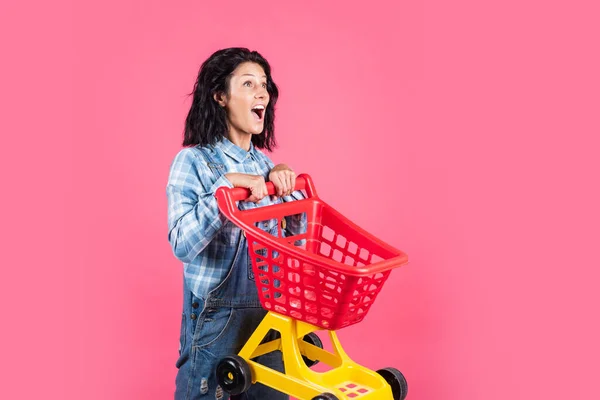 Příjemné nakupování. happy girl hold shopping cart. Kupující v supermarketu. zákazník s prázdným vozíkem. nakupující žena s vozíkem v supermarketu. žena nakupování v supermarketu tlačení vozík — Stock fotografie