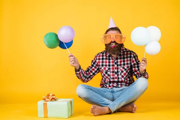 Mutlu, sakallı, sakalsız ve şık saçlı yakışıklı adam. Günlük kıyafetler giyer, hediye tutar, parti balonları, doğum günü tatili. — Stok fotoğraf