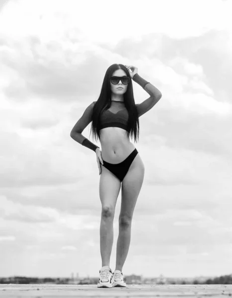 Αθλητικό κορίτσι τέλειο σώμα. Κέντρο σπα. Καλοκαιρινό σώμα Νιώθει ελεύθερη να εκφράσει τον αισθησιασμό της. Κορίτσι ελκυστικό σέξι σώμα θέτει φόντο ουρανό. Μια γυναίκα φοράει γυαλιά ηλίου και μπικίνι. Λεπτή μέση και μακριά πόδια — Φωτογραφία Αρχείου