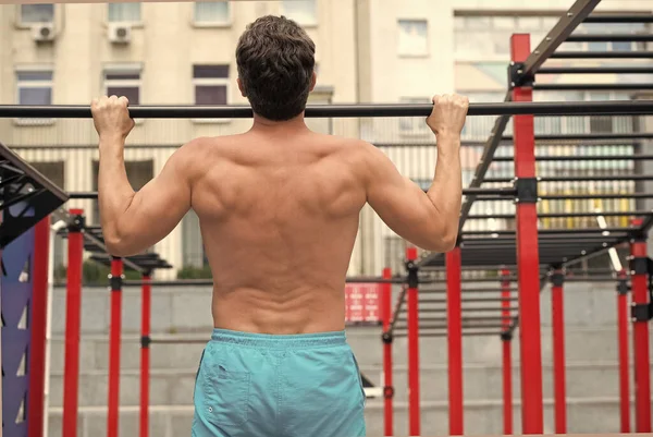 Achteraanzicht van de man in de sportschool. begrip sport. oefeningen in de fitnessruimte. Mannelijke shirtloze model doen oefeningen buiten. De fitte atleet doet oefeningen in het stadion. gezond zijn — Stockfoto