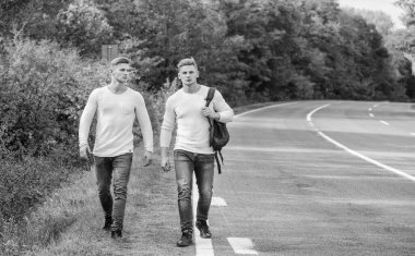 Arabanın kolayca kenara çekebileceği bir yer seç. Erkekler sırt çantasıyla yürüme yolu. İkizler yol boyunca yürür. Macera konsepti. Yolda otostop çeken adamlar. Turist gezgini otomobil durağında durur. Sorunlar taşınıyor