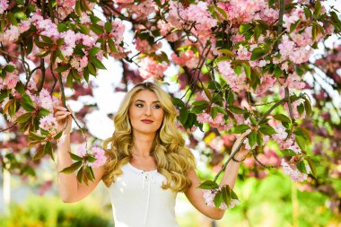 Bahar çiçeği açan ağaç. Mutlu bahar günleri. Kız bahçede sakura çiçeğinin tadını çıkarıyor. Kiraz ağacı. Çiçek aroması. Uyum ve kadın enerjisi. Bahar sembolü Çiçeklerin kadınları neden her zaman mutlu ettiğini.