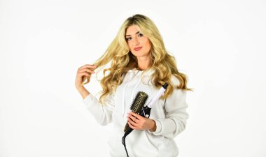 Çevrimiçi iş. Herkesin bilmesi gereken yararlı saç maşası hileleri. Saç stilini saç maşasıyla oluşturun. Uzun kıvırcık saçlı kadın saç maşası kullanıyor. Kuaför ipuçları. Sevimli sarışın kız. Araçları satın al