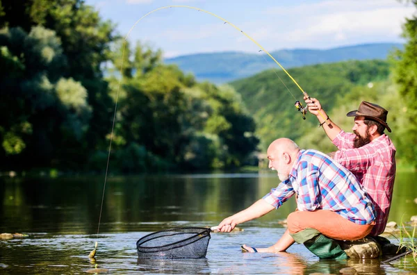 Grande jogo de pesca. mosca peixe passatempo dos homens. pesca da reforma. felizes pescadores amizade. Dois amigos a pescar juntos. Captura e pesca. aposentado pai e maduro barbudo filho — Fotografia de Stock