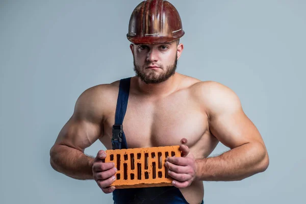 handsome man wear work clothes and helmet while working with brick, architecture