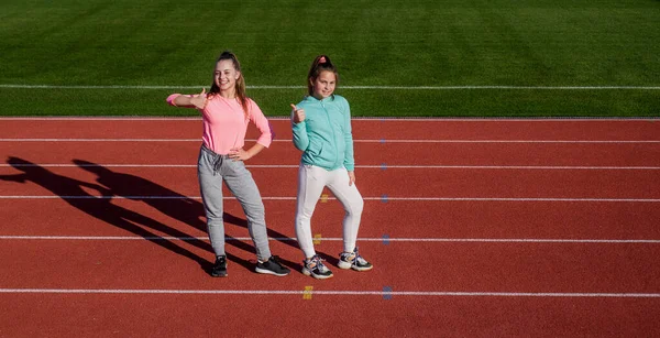 Happy fit meninas mostrar polegares de pé na pista de atletismo, aptidão física e promoção de esportes — Fotografia de Stock