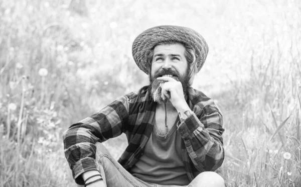 relaxed farmer in straw hat. mature man gardener relax on green grass. enjoy spring nature. summer season in perfect. brutal ranch hipster wear checkered shirt. farming and agriculture. Green life