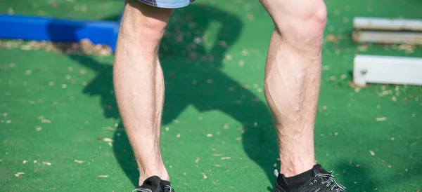 Man muscular legs in black sport fashion shoes at stadium — Stock Photo, Image