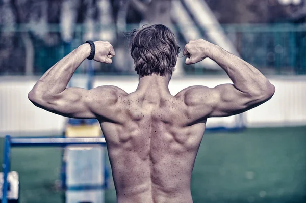 Homme athlétique a le dos musclé avec des taches de rousseur, se faisant passer pour bodybuilder — Photo