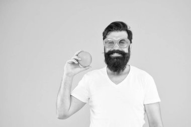 Meyve suyu. Sarı arka planda turuncu güneş gözlüklü sakallı hippi. Olgun meyveli neşeli adam. Yaz tatili. Taze ve sağlıklı. Yaz beslenmesi. Yaz havasında sakallı hippi.