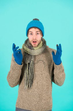 Şok olmuş bir adam kışın üşüyor. Grip yok. Kış hava tahmini. Adam kalın kıyafetler giyiyor. Erkek örgü modası. Erkekler kumaş ve aksesuar örer. erkek mavi arka plan. Zavallı evsiz adam.