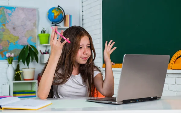 Den znalostí. dítě žák sedět u stolu a používat počítač. Ta holka je vysokoškolačka. Zpátky do školy. dospívající dívka pracovat ve třídě s notebookem. Veselé dítě se učí předmět online. moderní vzdělávání — Stock fotografie