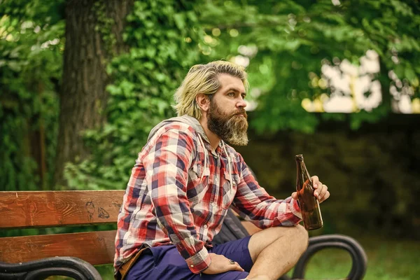 Summer rest concept. Man enjoying beer in park. Guy on bench in park drinking beer. Modern hipster relaxing. You deserve fine relax. Craft beer. Hipster bearded man hold cold fresh beer bottle — Stock Photo, Image